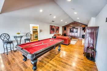 A game room with a red pool table and a bar